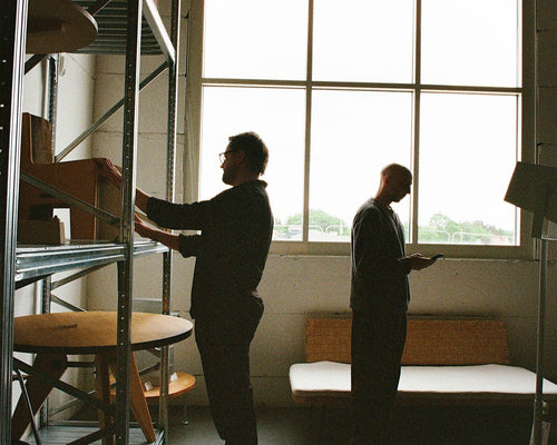 Two men in a room with shelves and a large window