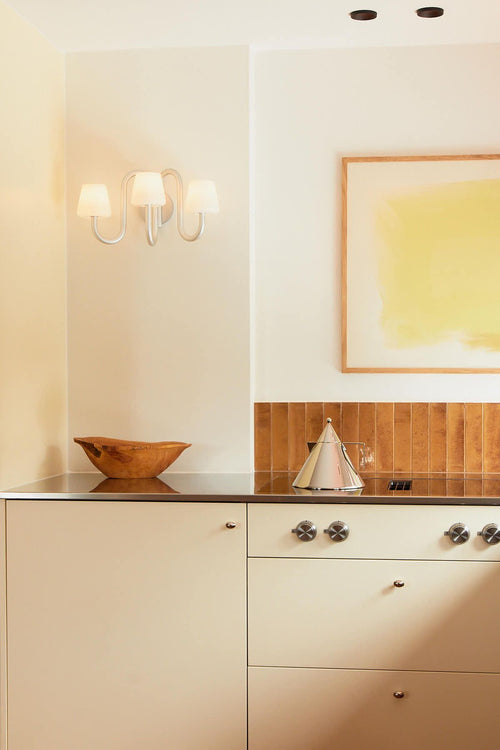 Modern kitchen with wooden backsplash, countertop, and abstract art on wall.