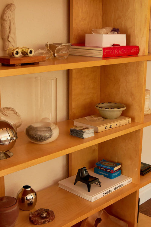 Wooden bookshelf with decorative items including books, vases, and a small statue.