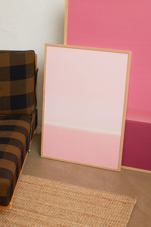 Art print with an abstract spray painting of a sky in light pink tones. Styled in a minimalist interior.