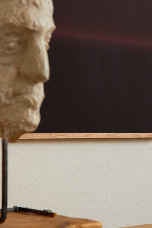 Art print with an abstract spray painting of a dark sky in deep purple tones. Styled in a minimalist interior.