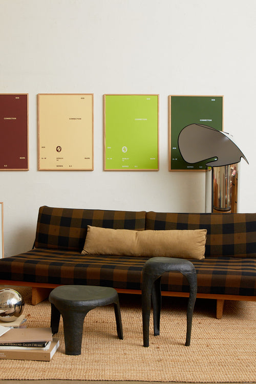 Art print with minimalist, small graphic text elements and a symbol motif in white against a lime green background. Styled in a minimalist interior.