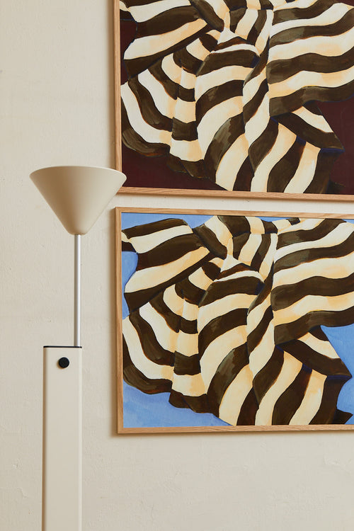 Art print featuring a painting of a plaid against a sky-blue background, flowing with wide stripes in dark chocolate brown and creamy white. Styled in a minimalist interior.