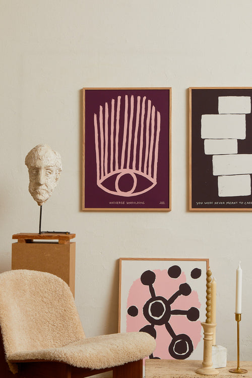 Art print with an abstract colorful, minimalist painting in purple and pink that references an eye. Styled in a minimalist interior.