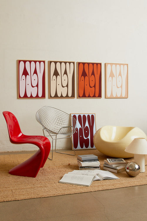 Art print featuring playful, bold typography of the word “Baby” in rust orange against a dark brown background. Styled in a minimalist interior.