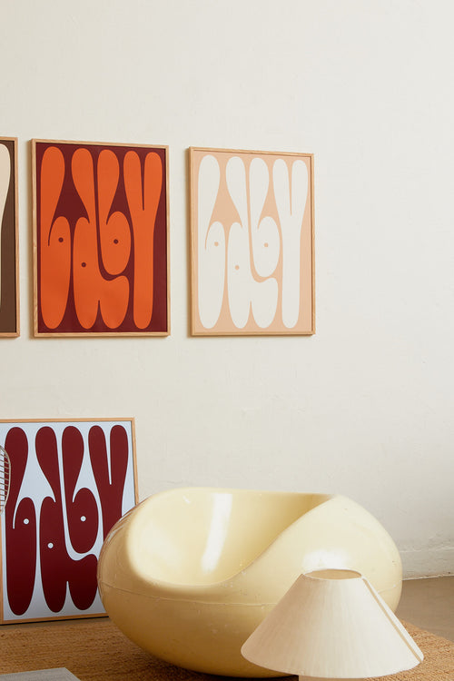 Art print featuring playful, bold typography of the word “Baby” in rust orange against a dark brown background. Styled in a minimalist interior.