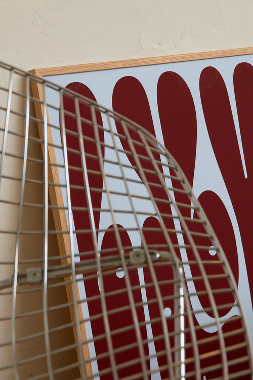 Art print featuring playful, bold typography of the word “Baby” in burgundy against a light blue background. Styled in a minimalist interior.