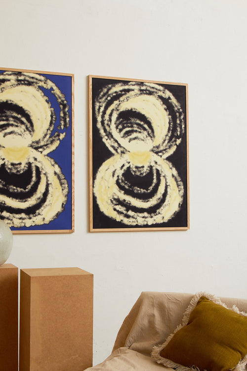 Art print with an abstract illustration of circular forms in light tones against a dark background, with a soft and organic expression. Styled in a minimalist interior.