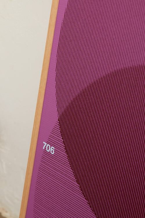 Art print with a graphic illustration of circular forms built from overlapping lines, complemented by small text elements, in purple and blue RAL colors. Styled in a minimalist interior.