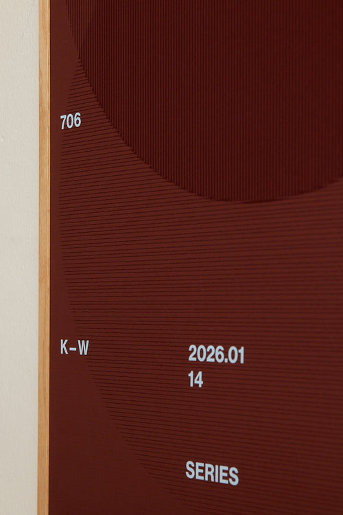 Art print with a graphic illustration of circular forms built from overlapping lines, complemented by small text elements, in brown, blue, and red RAL colors. Styled in a minimalist interior.