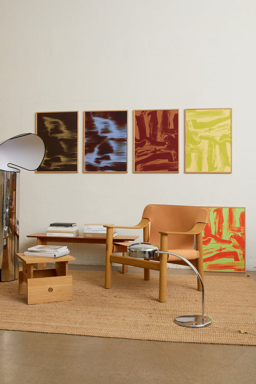 Art print featuring layered and sweeping brushstrokes in light yellow and green that create a sense of movement and tension across the surface. Styled in a minimalist interior.