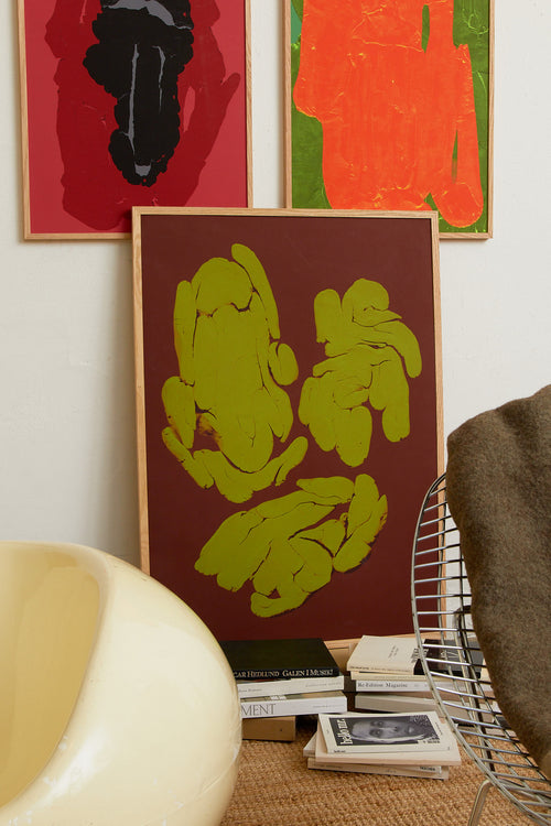 Art print featuring fragmented, rounded forms arranged in loose groupings across a deep brown surface, with subtle cracks and glowing edges. Styled in a minimalist interior.