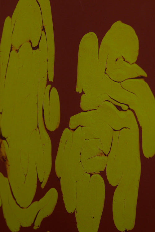 Art print featuring fragmented, rounded forms arranged in loose groupings across a deep brown surface, with subtle cracks and glowing edges. Styled in a minimalist interior.