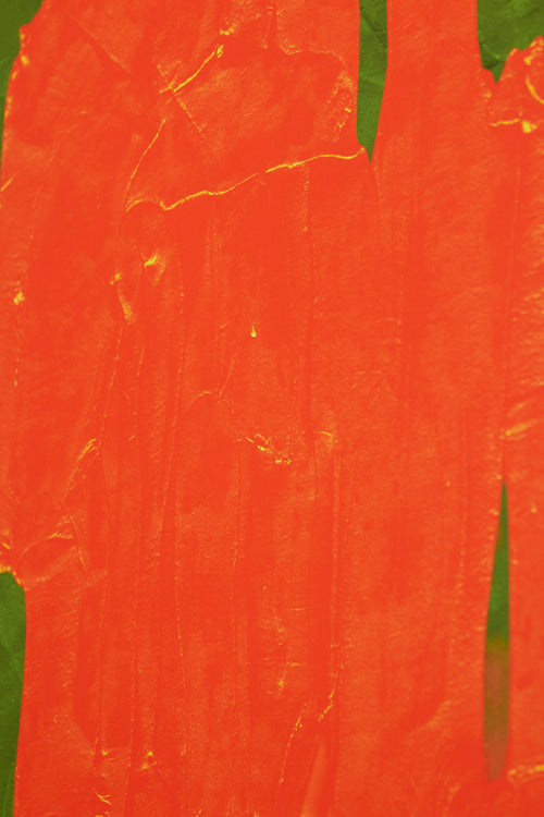 Art print featuring soft, blurred, and flowing bright orange shapes emerging against a dark green surface, creating an impression of motion and impermanence. Styled in a minimalist interior.