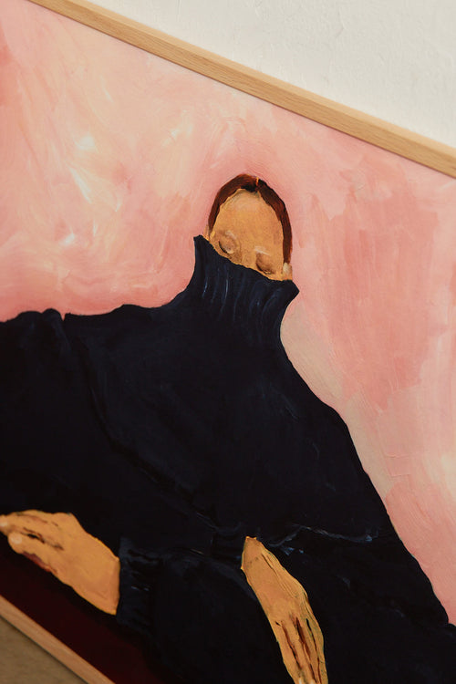 Art print featuring a figurative painting of a seated person in an oversized dark sweater, with the face partially hidden, against a light pink background. Styled in a minimalist interior.