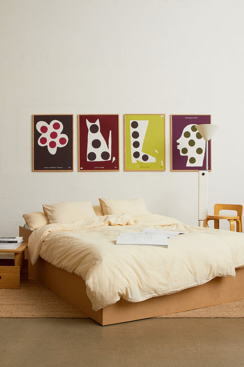 Bedroom interior scene with the burgundy “Creative mind” print displayed alongside other colorful artworks above the bed
