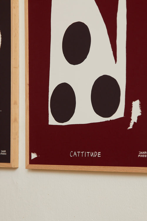 Interior bedroom scene with the red “Cat’s face” print displayed alongside other artworks