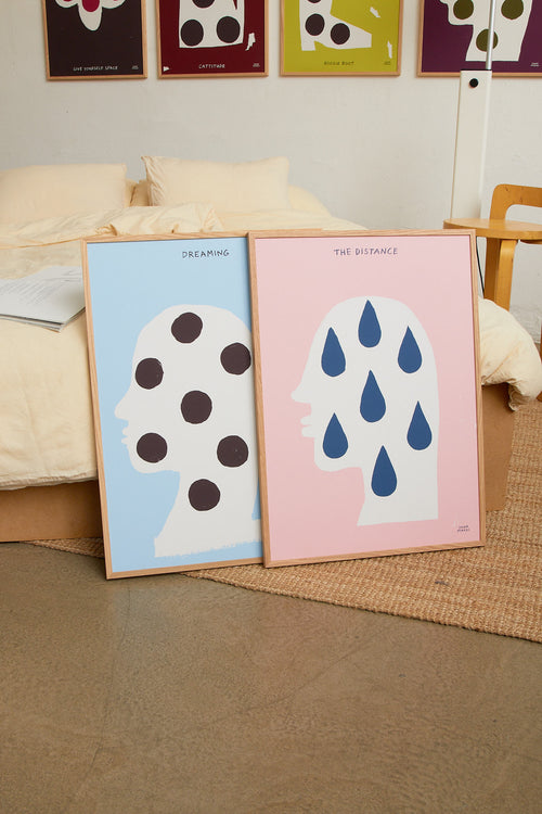 Art print featuring a silhouette of a head in profile with drops and the handwritten note “The Distance”. Styled in a minimalist interior.