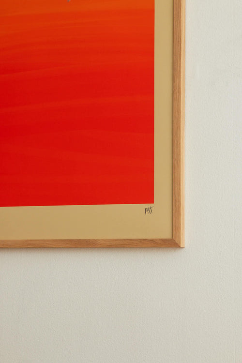 Framed abstract artwork with a red background and gold frame on a light gray wall.