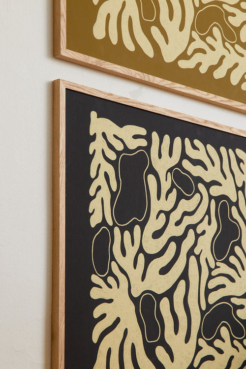 Two abstract art pieces with gold and black patterns on a light wall.