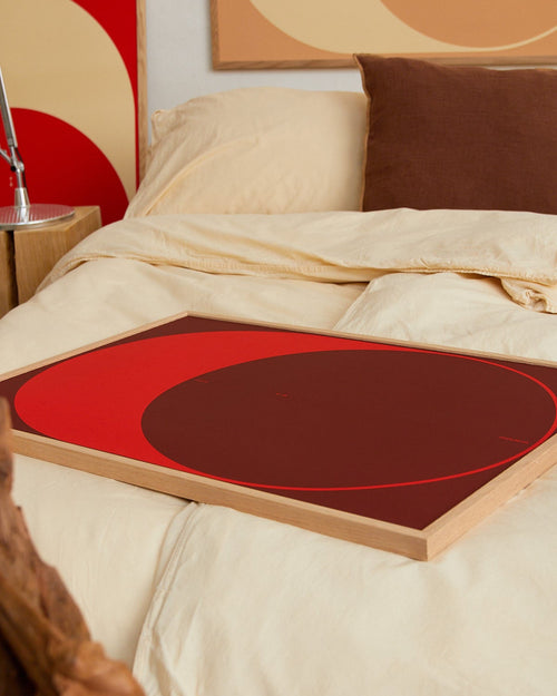 Red circular object on a bed with abstract art in the background