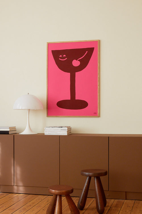 Simplified illustration of a cocktail glass with a cherry on a pink background