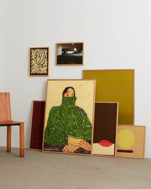 Collection of framed artworks on a light gray floor with a white wall background