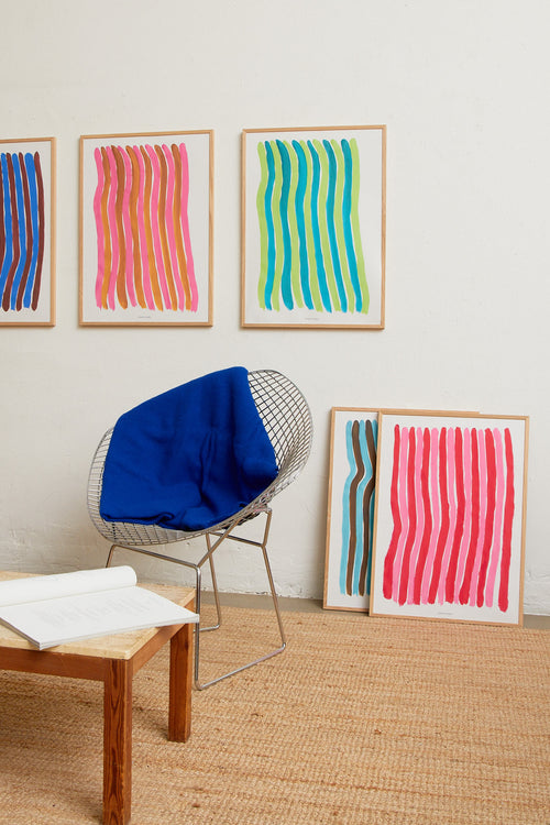 Green striped print styled in a modern interior with chair and blue throw