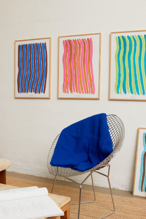 Pink striped print styled in a modern interior with chair and blue throw