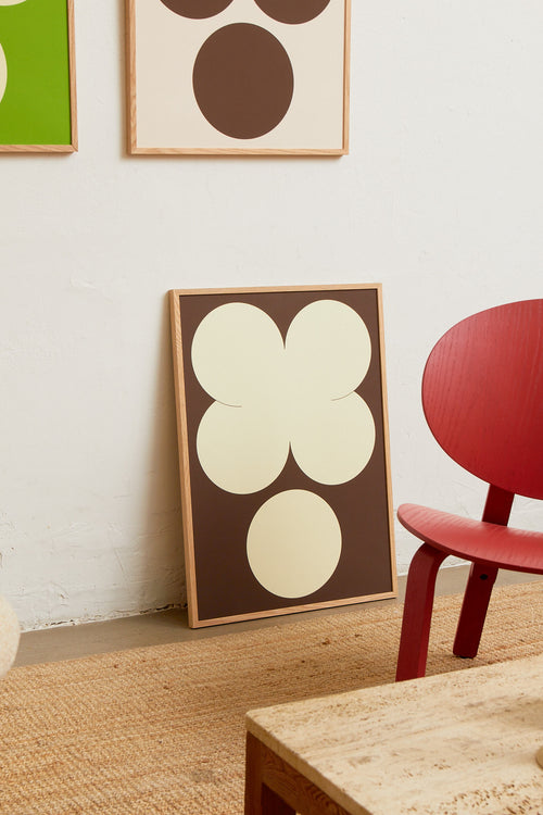 Art print featuring playful, bold typography of the letters X and O, hugs and kisses, in off-white against a dark brown background. Styled in a minimalist interior.