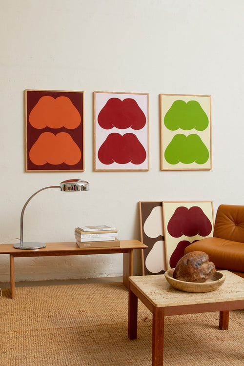 Art print featuring playful, bold typography of the text “MM”, the sound of enjoyment, in rust orange against a dark brown background. Styled in a minimalist interior.