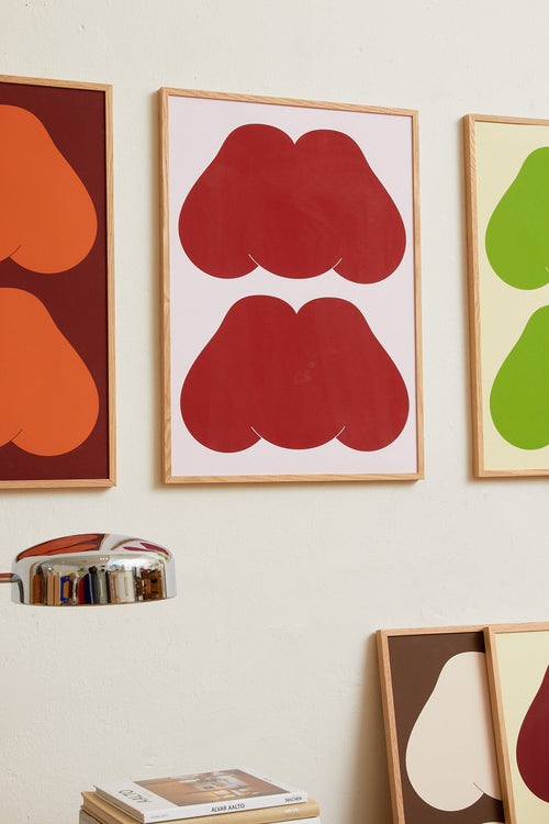 Art print featuring playful, bold typography of the text “MM”, the sound of enjoyment, in red against a pink background. Styled in a minimalist interior.