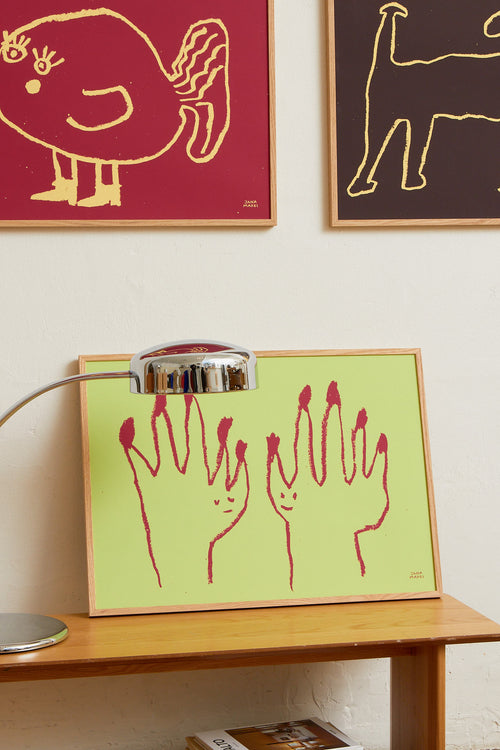 Interior scene with the green hands print displayed alongside other colorful artworks on a wall