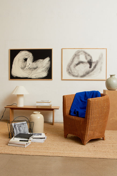 Art print with a stylized illustration of a swan in gray tones against a, with a soft and graphic expression. Styled in a minimalist interior.