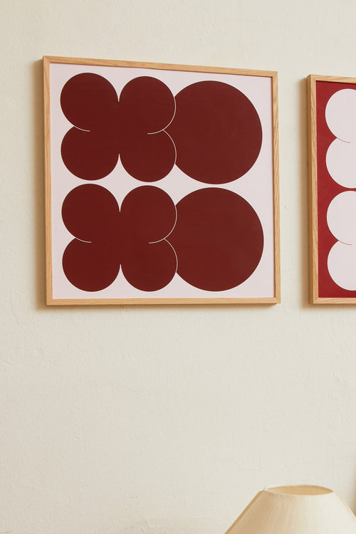 Square-format Art print featuring playful, bold typography of the letters X and O, hugs and kisses, in burgundy against a pink background. Styled in a minimalist interior.