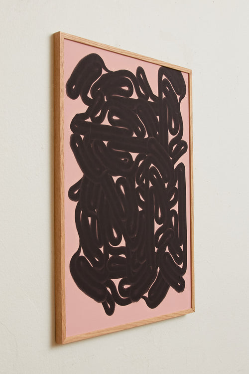Art print featuring dense, black rounded forms with a smooth, glossy feeling emerging against a warm, light pink background. Styled in a minimalist interior.