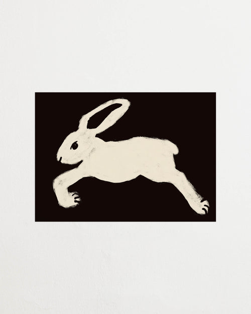 Art print with a stylized illustration of a hare in a light tone against a black background, with a minimalist and graphic expression. Styled in a minimalist interior.