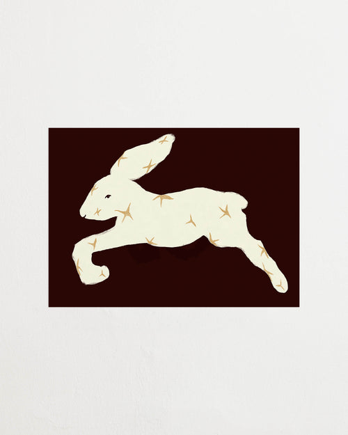 Art print with a stylized illustration of a hare in a light tone with stars against a dark brown background, with a minimalist and graphic expression. Styled in a minimalist interior.