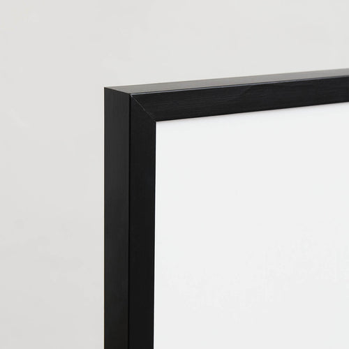 A close-up of the corner of the Black wooden frame showcases its simple and modern design against a white background and a light gray wall.