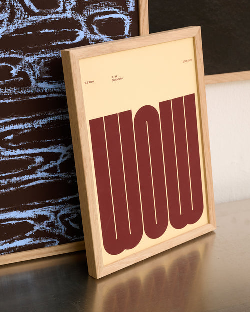 A framed typographic art print leaning on a reflective surface, featuring the word 